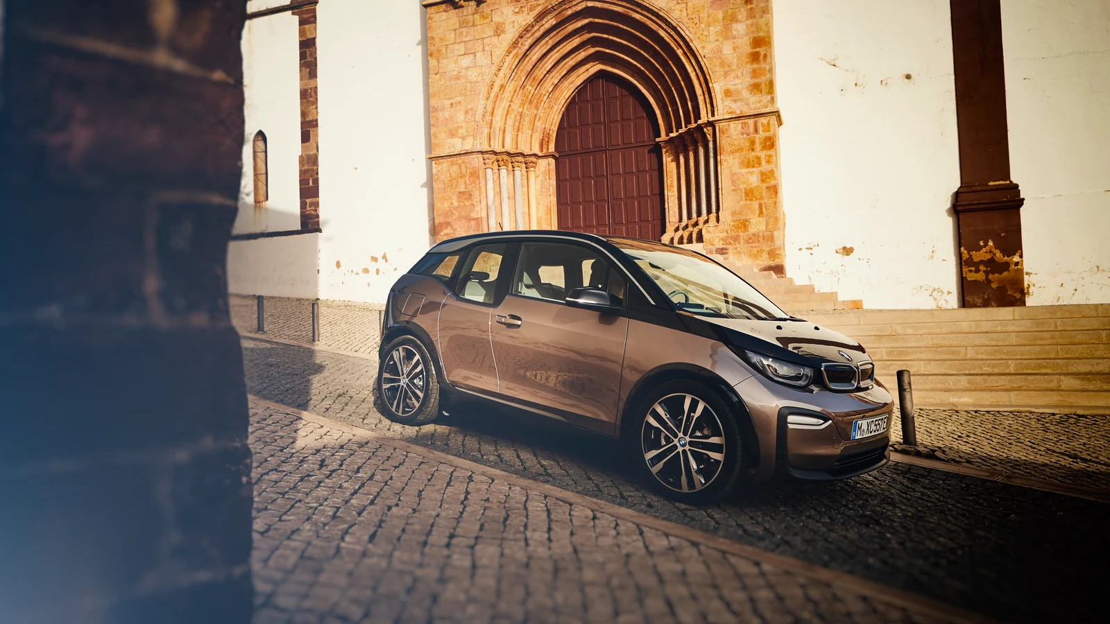 Jucaro Bej BMW i3 120 Ah, taş sokakta ön üç çeyrek açıyla park halinde
