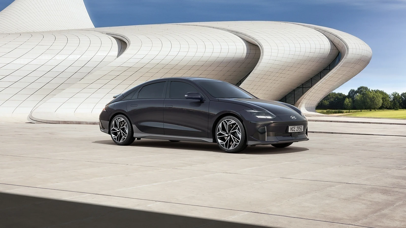 Mimari yapının önünde koyu gri Hyundai IONIQ 6 ön üç çeyrek görünümü