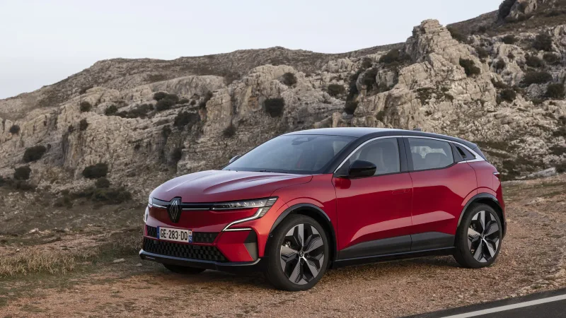 Kırmızı Renault Megane E-Tech’in kayalık yol kenarında ön çapraz görünümü