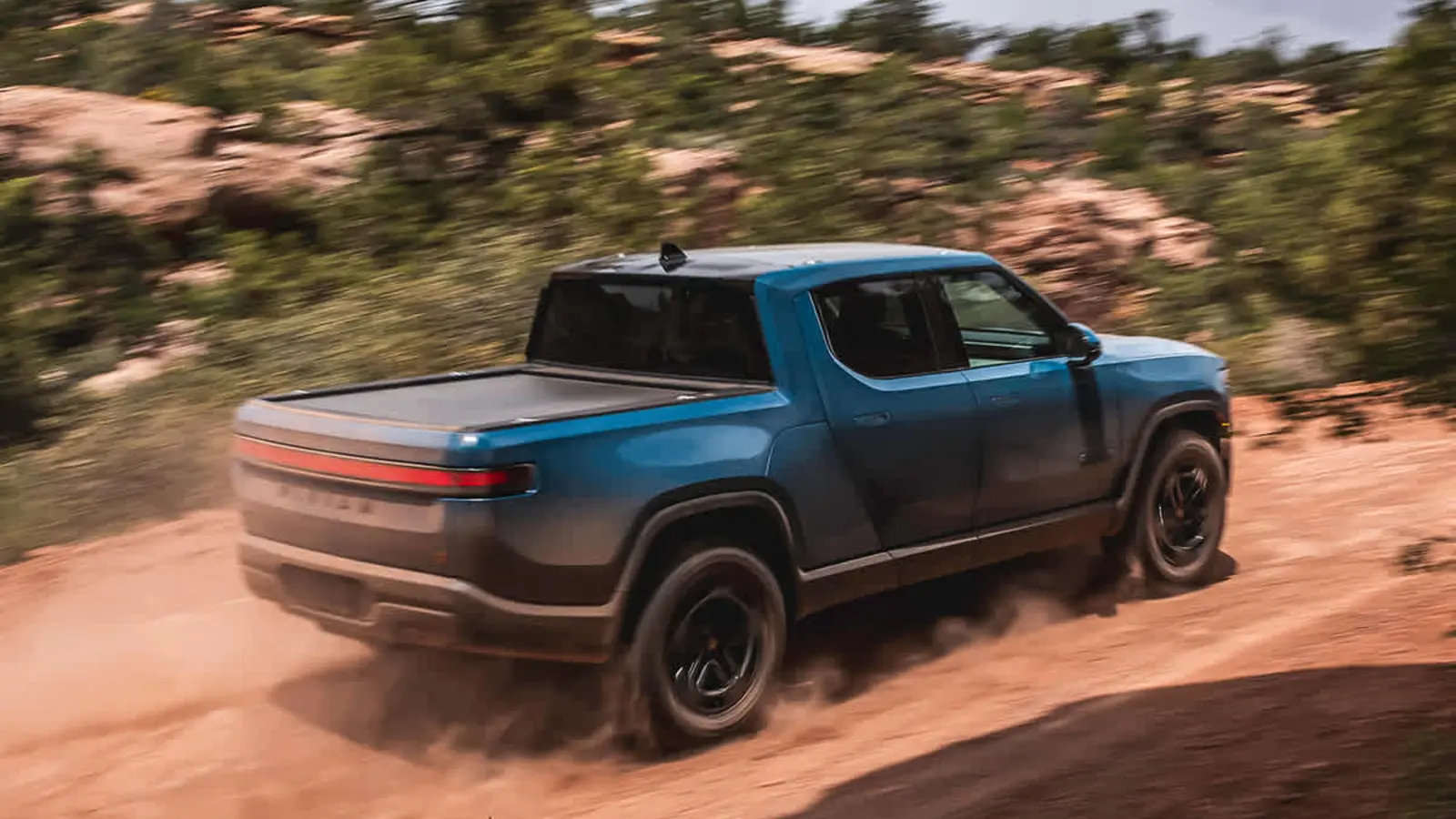 Mavi Rivian R1T doğal zeminde sürüşte