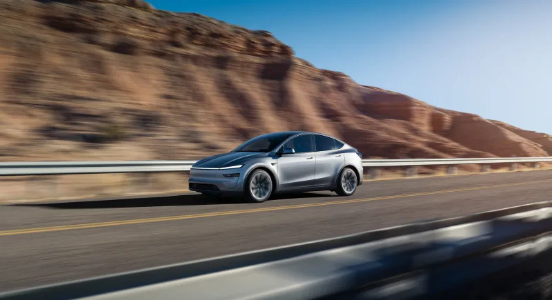 Gümüş Tesla Model Y Premium vadide ön üç çeyrek sürüş görünümü